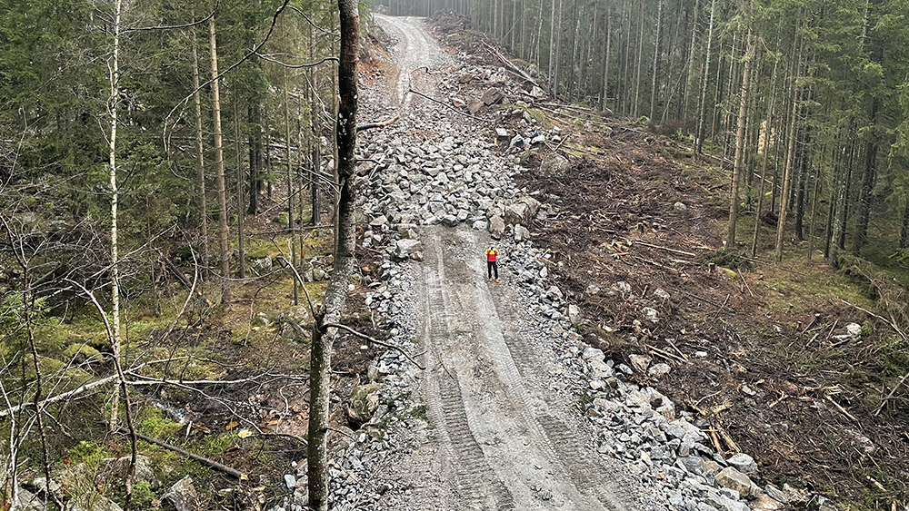 Mann som står på en skogsvei som er under bygging. Foto.